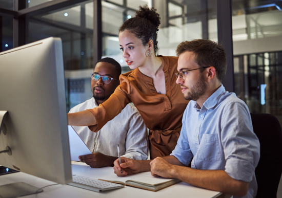 Three employees working together while sharing a single computer screen