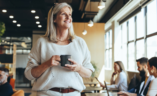 A woman smiling holding a cup of coffee