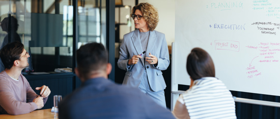 One person presenting to a seated group from a whiteboard